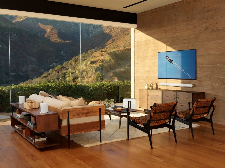 A living room with large picture windows and a Sonos sound system and flat-screen TV.